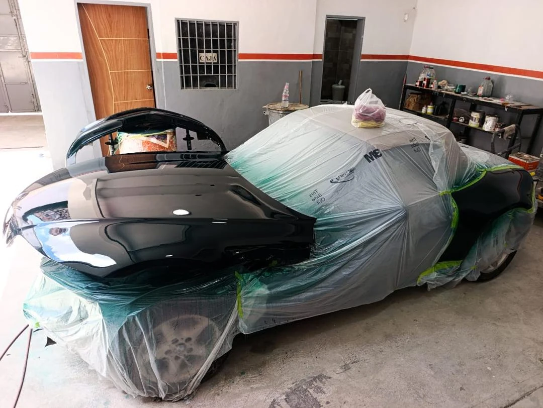 Carro negro con zonas enmascaradas durante la preparación para pintura en el taller