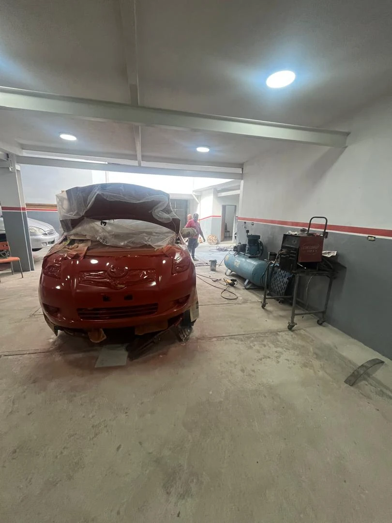 Frente de un carro rojo durante un trabajo de pintura en el taller